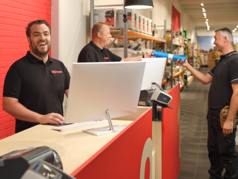 Hijman medewerker helpt klant met schoonmaakartikelen afrekenen in de winkel
